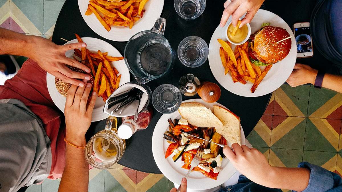 Close up of four plates of food with hands