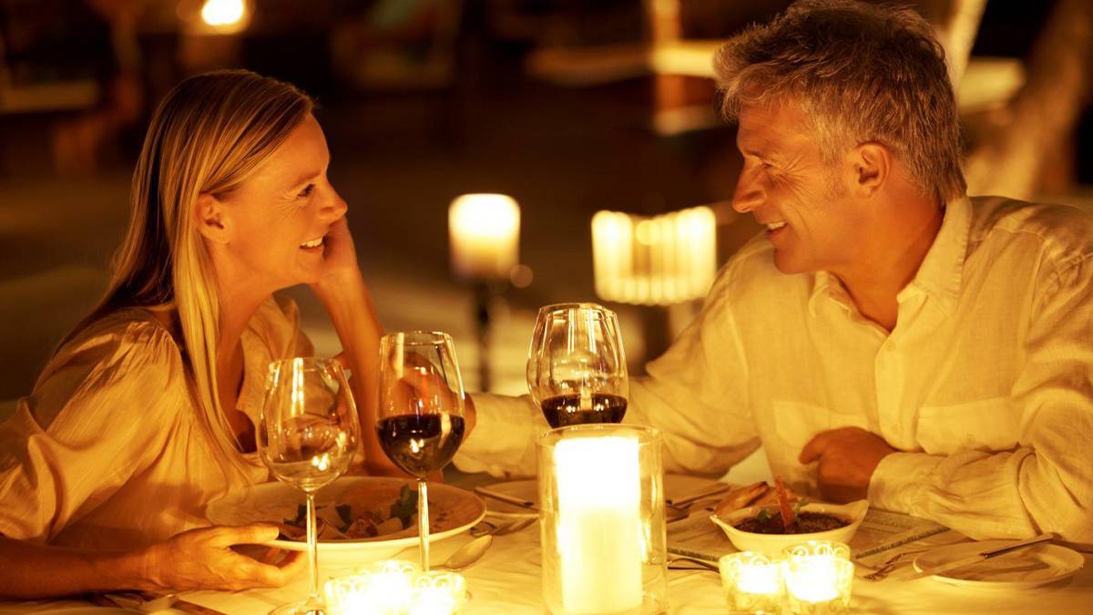 Man and woman drinking wine over romantic candlelight dinner