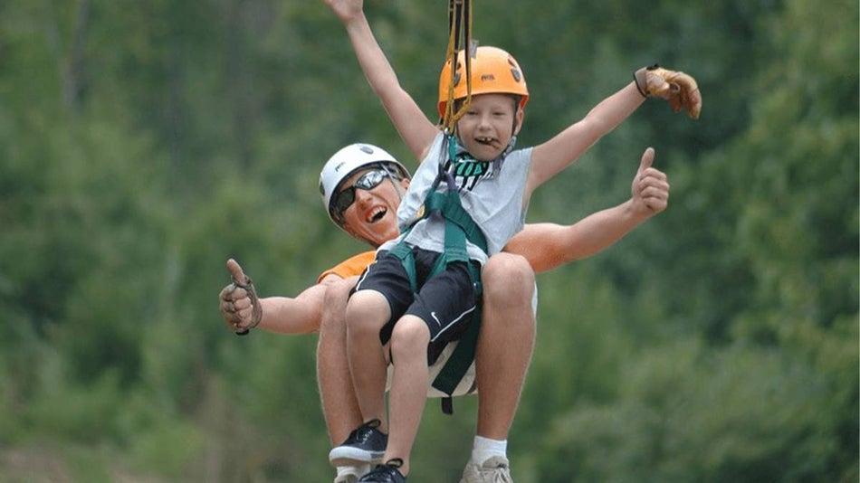father and son ziplining through woods