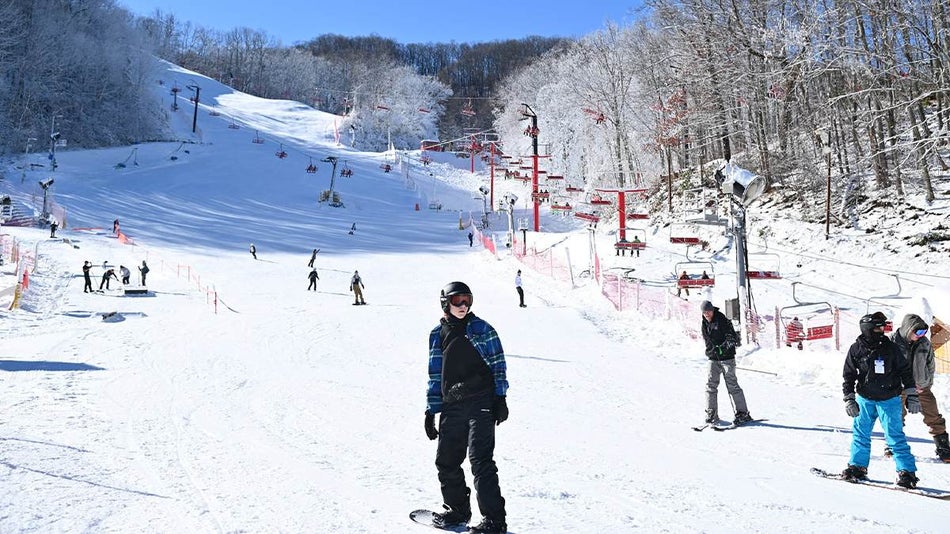 Wide shot of people snowboarding down the slopes at Ober Gatlinburg on a sunny day in Gatlinburg, Tennessee, USA