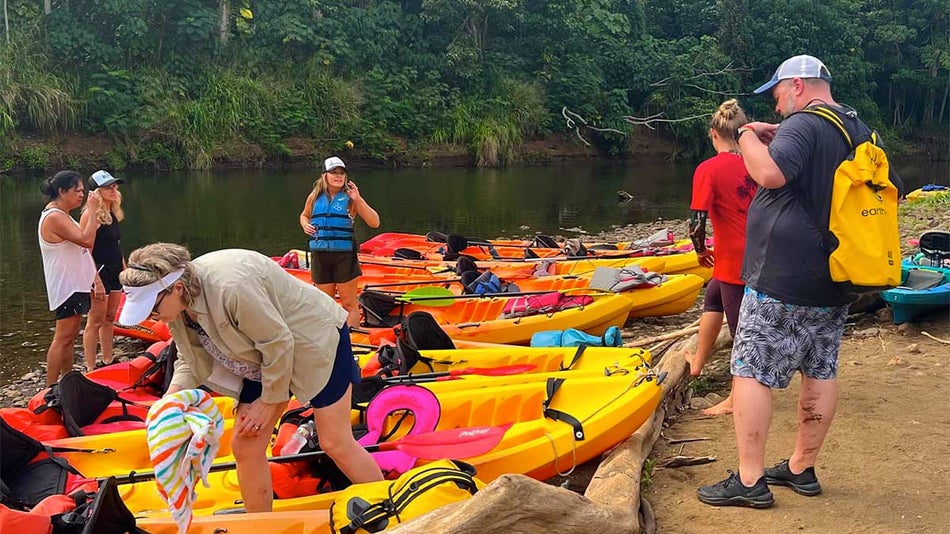 colorful kayaks lined up along river on a Wailua River Kayak Tour in Kauaʻi, Hawaii, USA