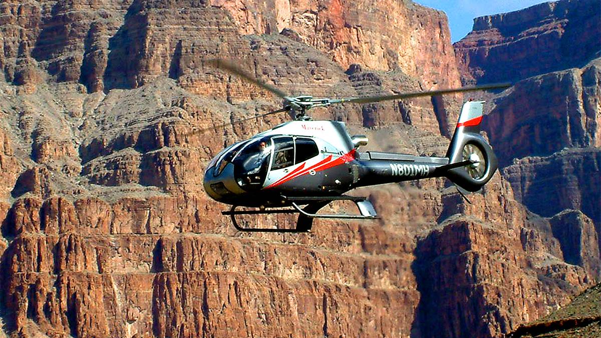 A grey red and white helicopter flying through the Grand Canyon on the Grand Canyon West Rim Ground & Helicopter Tour near Las Vegas, Nevada, USA