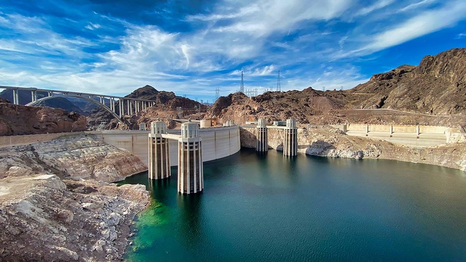Wide shot of the Hoover Dam in the daylight with the bridge in the background and very blue water in the reservoir in Las Vegas, Nevada