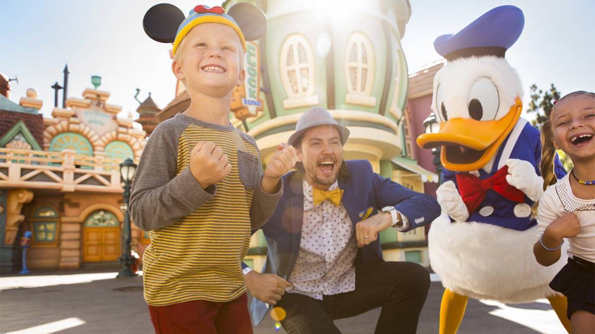 Excited kids standing with Donald Duck at Disneyland