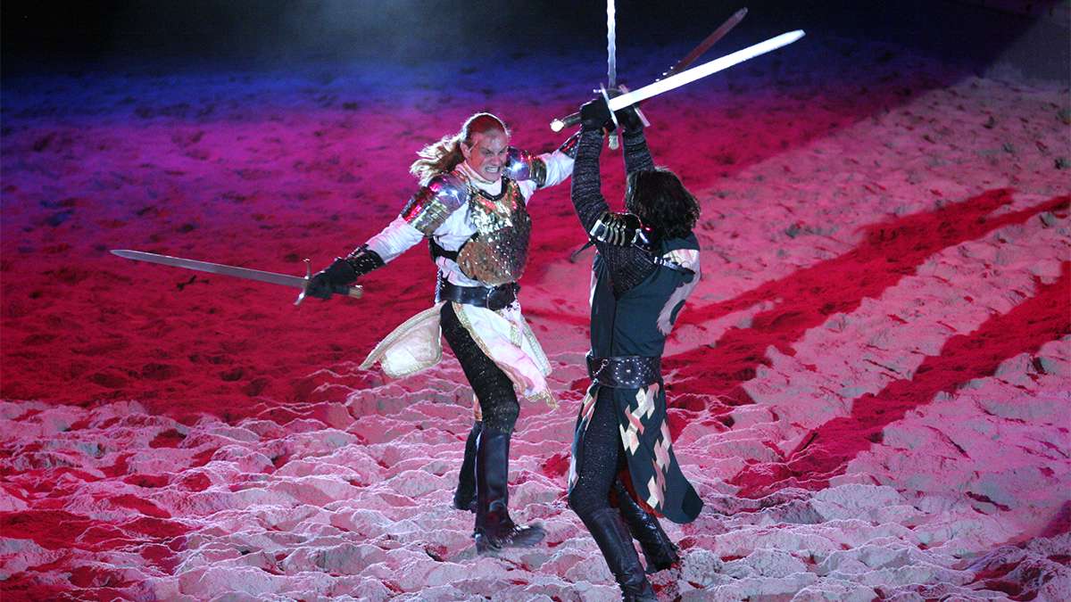 white knight and black knight sword fighting on performance floor at Medieval Times Dinner & Tournament in Los Angeles, California, USA