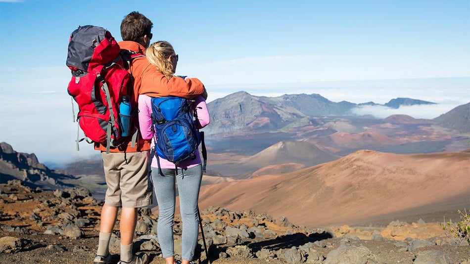 couple with hiking backpacks looking at the sunny view at Haleakalā East Maui Volcano in Maui, Hawaii, USA