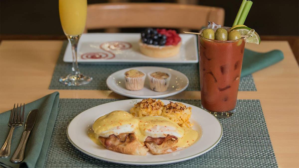 Close up photo of a brunch of eggs Benedict with a Bloody Mary on green place setting at Croissants Bistro and Bakery in Myrtle Beach, South Carolina, USA