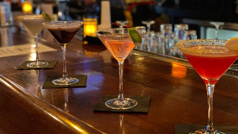 Close up photo of four different martinis on a dark wood bar at Greg Norman Australian Grille in Myrtle Beach, South Carolina, USA