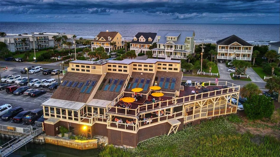 Aerial view of Gulfstream Cafe with people sitting in the outdoor dining area with bright yellow umbrella and the ocean in the back ground with dark clouds over head in Myrtle Beach, South Carolina, USA