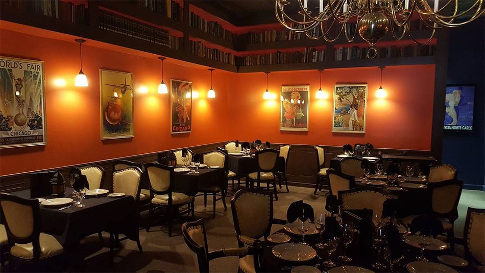 A dimly lit dining room with books lining the upper part of the wall and ornate chairs and tables at The Library Restaurant in Myrtle Beach, South Carolina, USA