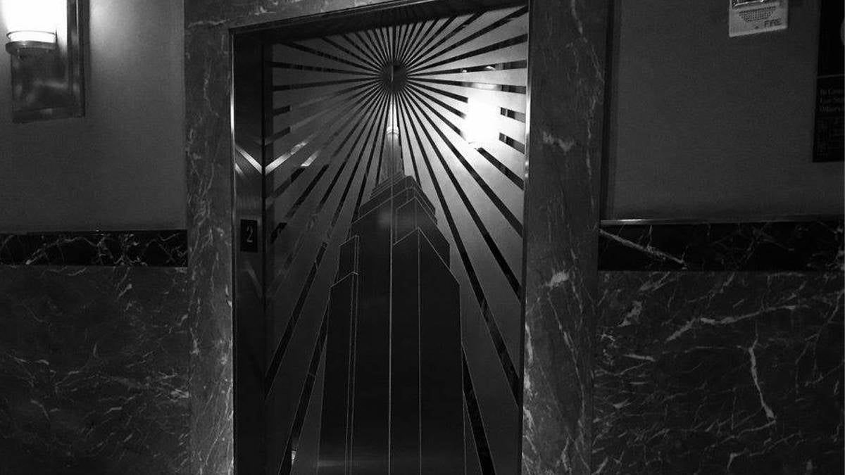 Black and white close up of the Otis Elevator doors in the Empire State Building with an image of the building on them in NYC, New York, USA