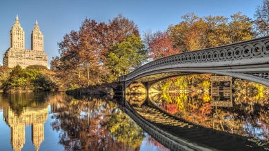 Close up of Bow Bridge over water with skyline with Central Park in background in NYC, New York, USA