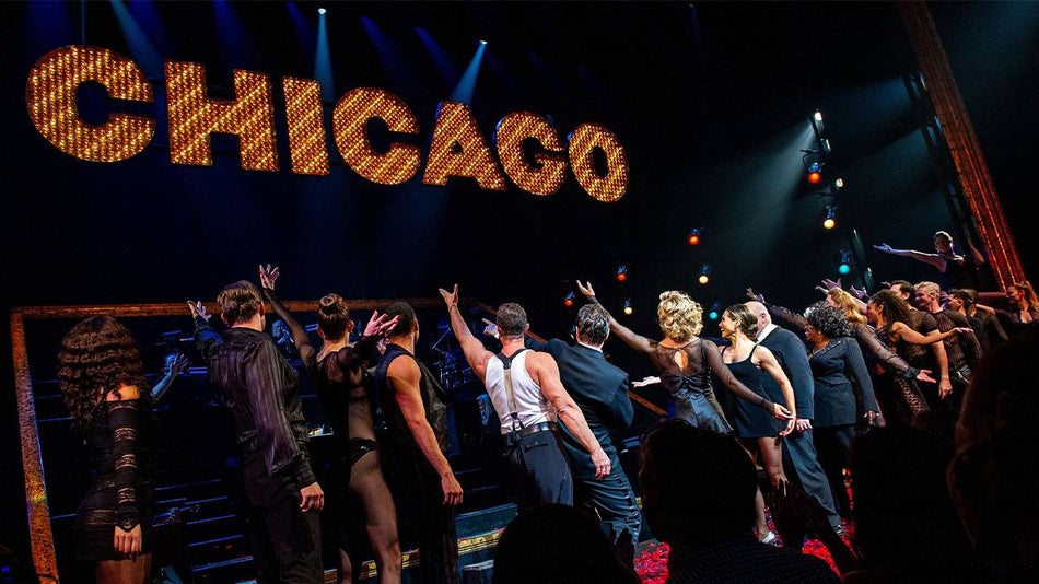 Close up photo of the cast of Chicago point up to a bright sign that says Chicago on Broadway in NYC, New York, USA