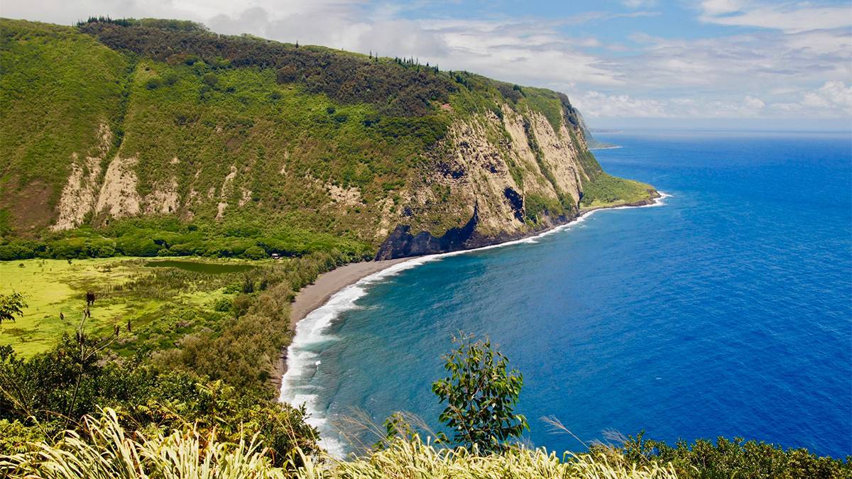 Wide shot of Waipi'o Valley Lookout on a sunny day with bright blue water in Oahu, Hawaii, USA