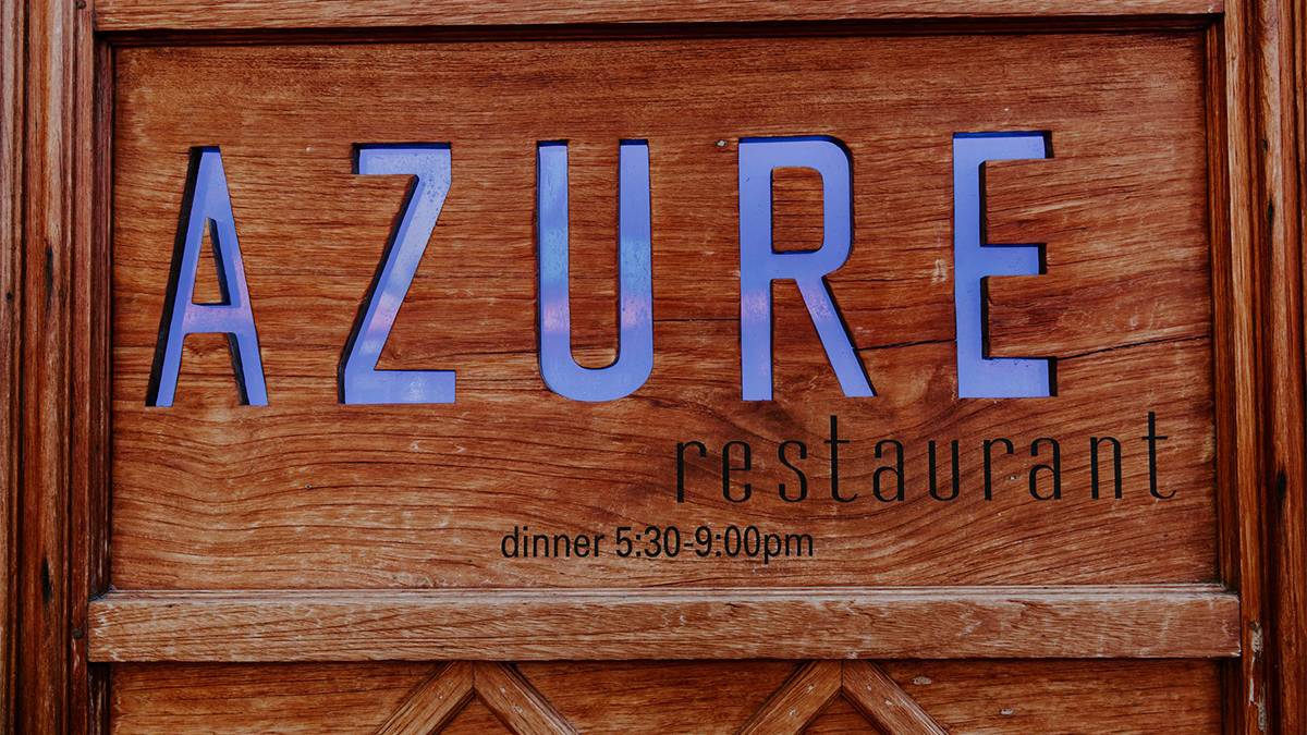 Close up view of a wooden sign with blue lettering for Azure restaurant in Oahu, Hawaii, USA