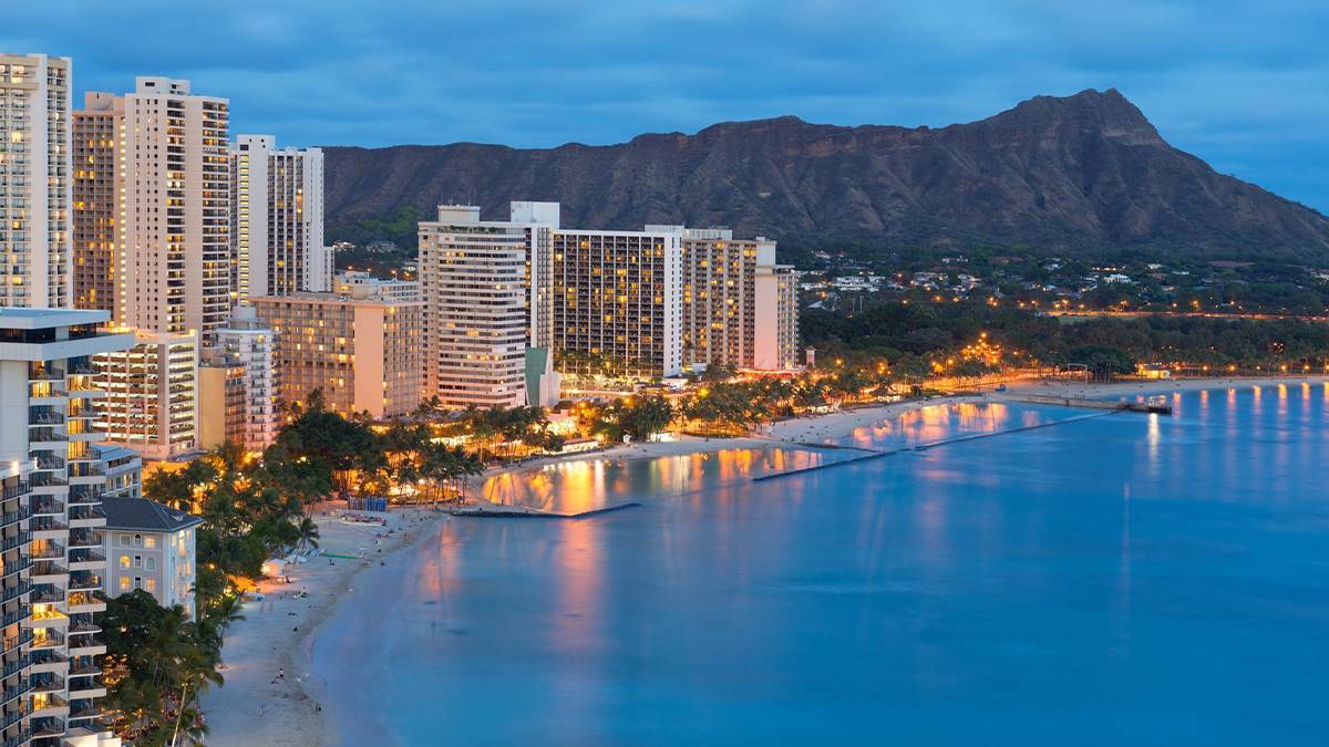 Aerial view over Diamond Head at night with lights on beach in Oahu, Hawaii, USA