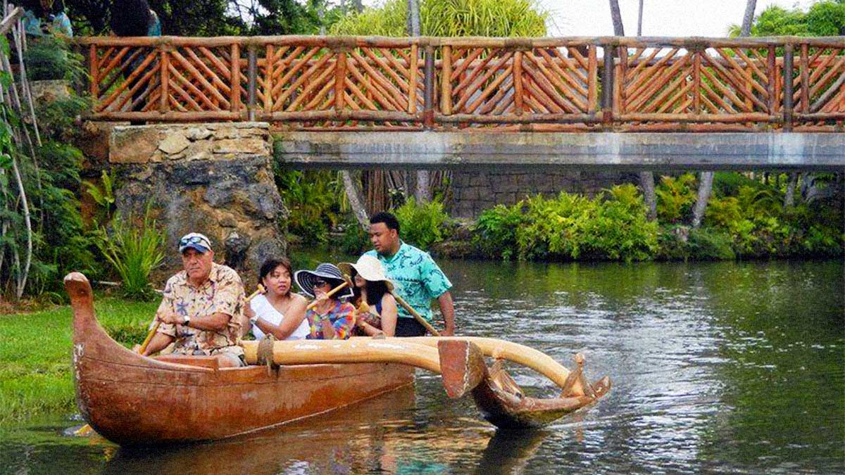 People in a canoe floating down a river at the Rainbows of Paradise Canoe Pageant at the Polynesian Cultural Center - Oahu, Hawaii, USA