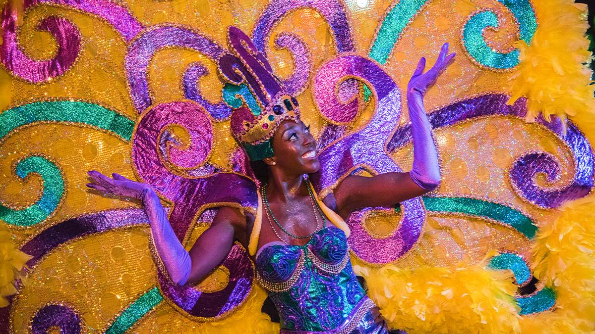 Close up of a performer in a large intricate Mardi Gras costumer with lots of green purple and yellow plus a crown at the Universal Orlando Resort Mardi Gras Parade in Orlando, Florida, USA