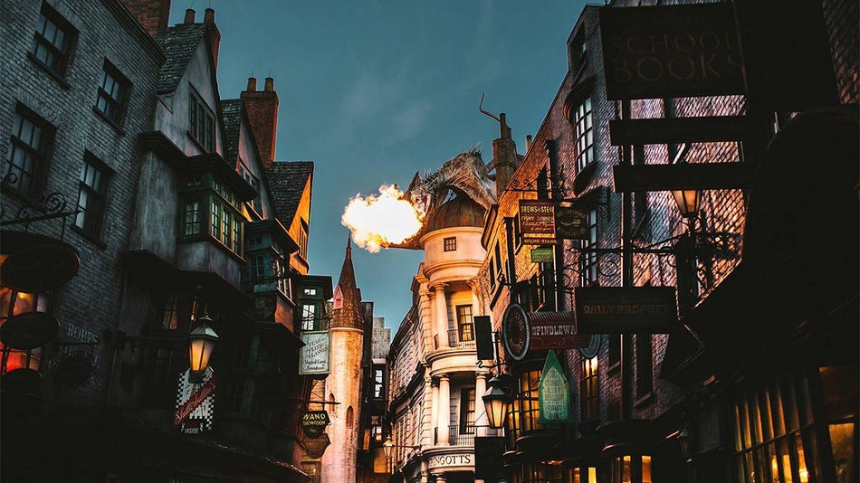 View of Diagon Alley at night with the dragon on top of Gringotts Bank breathing fire at Universal Studios in Orlando, Florida, USA