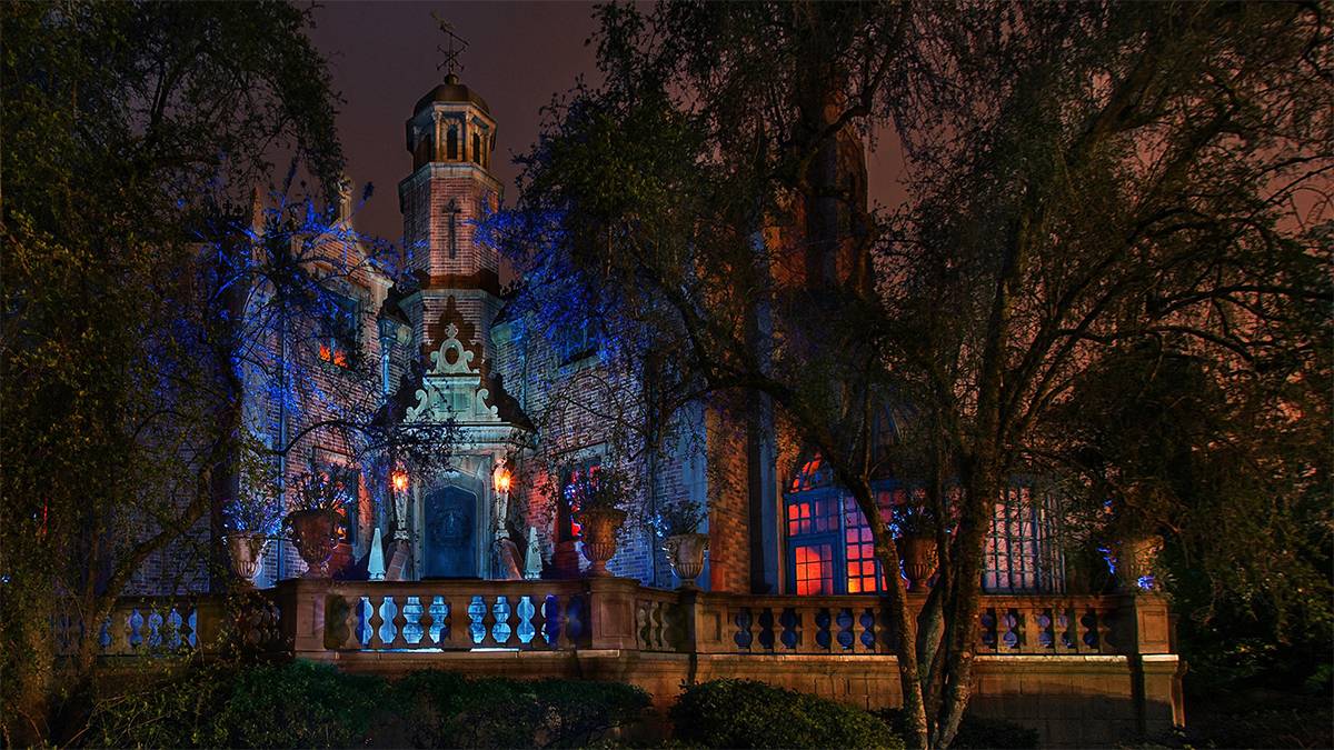 View looking up at the Haunted Mansion through the trees at night at Walt Disney World in Orlando, Florida, USA