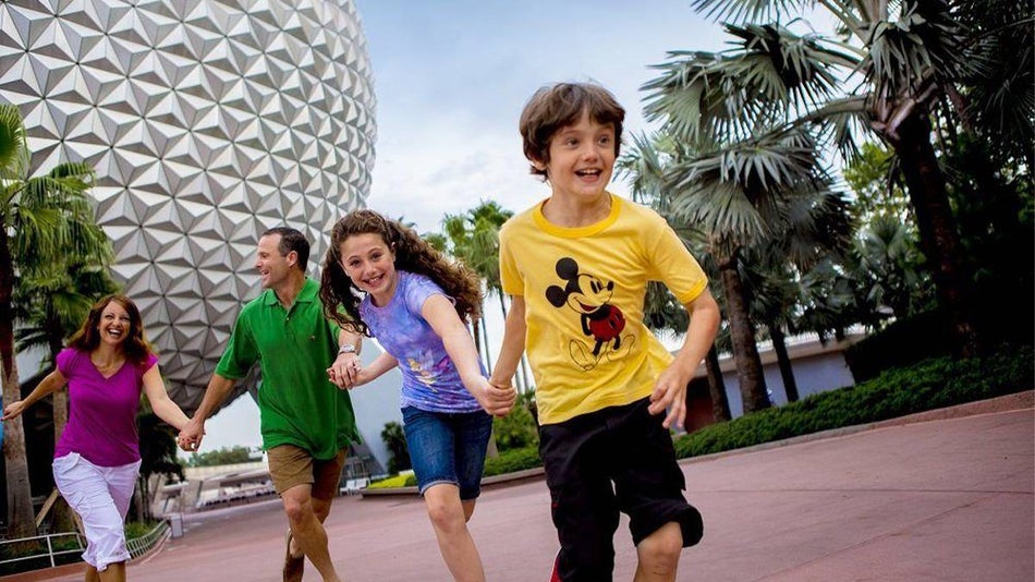 Family Running on the sidewalk with Space Ship Earth in the background at Walt Disney World's Epcot - Orlando, Florida, USA