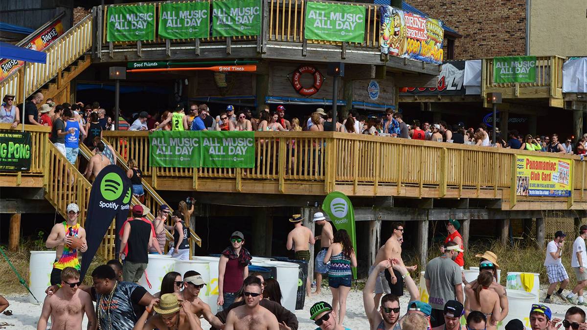 Wide shot of the deck and beach at Harpoon Harry's during spring break filled with people partying in Panama City Beach, Florida, USA