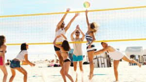 Close up of a group of young friends playing beach volleyball