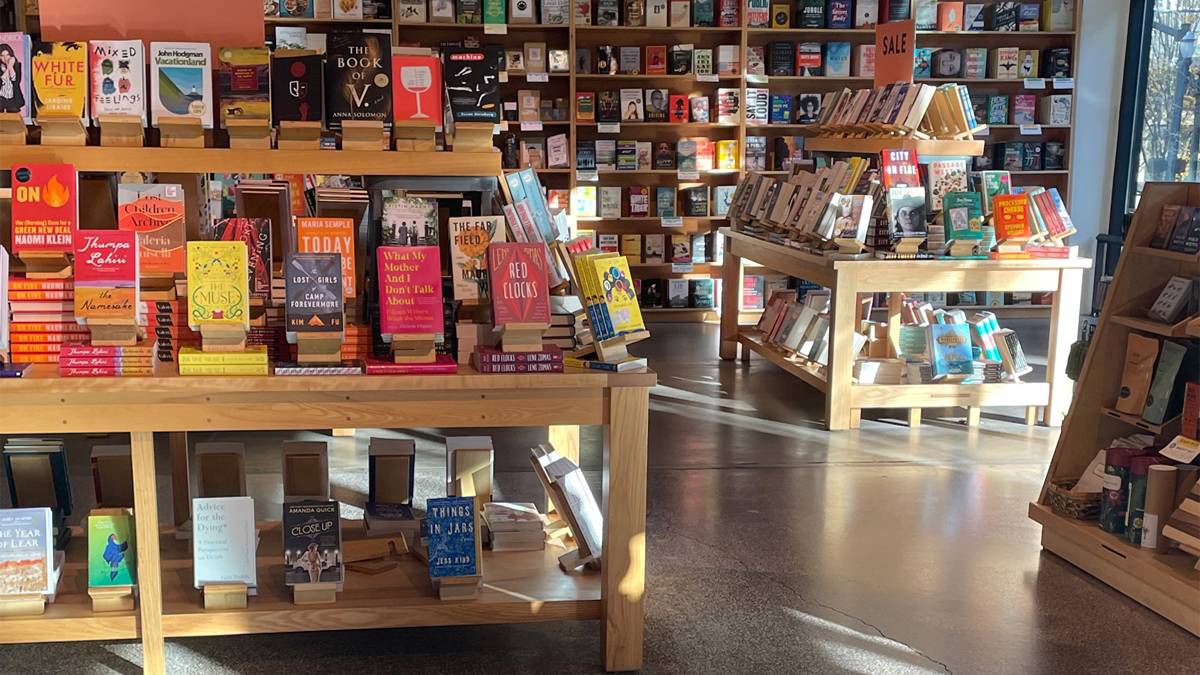 View of several book displaces with a wall of books in the background and light coming in a window to the right at Powell’s City of Books in Portland, Oregon, USA