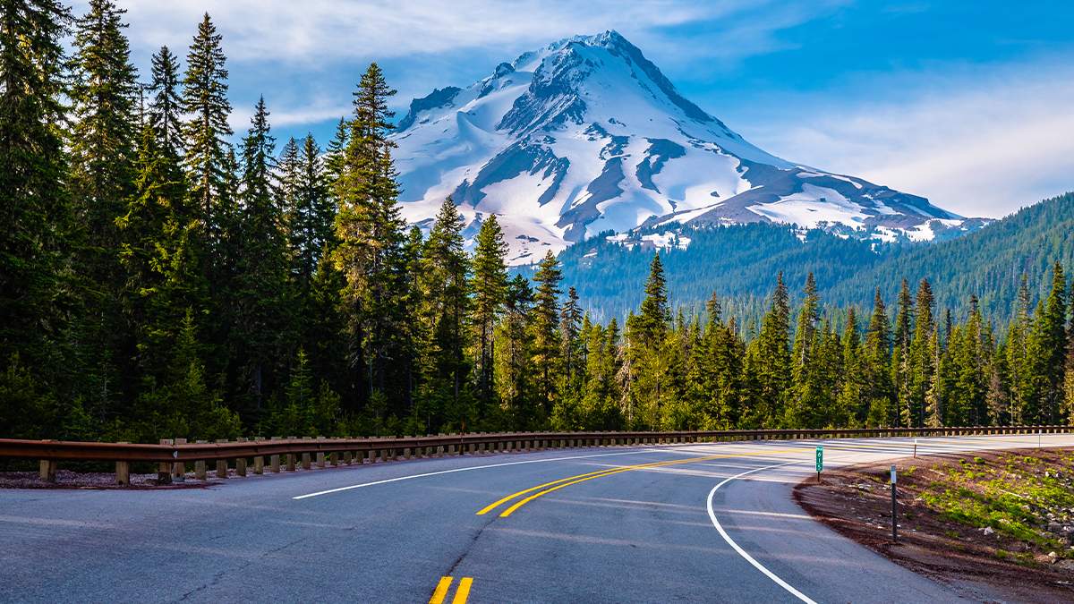 View of Mount Hood with clear skies from the highway with trees lining it near Portland, Oregon, USA