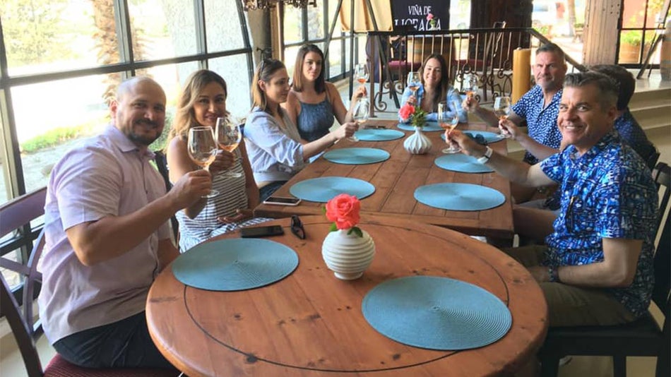 View of a table full of people with wine glasses smiling for the photo on the Luxury Private Wine Tasting Tour to Guadalupe Valley in San Diego, California, USA