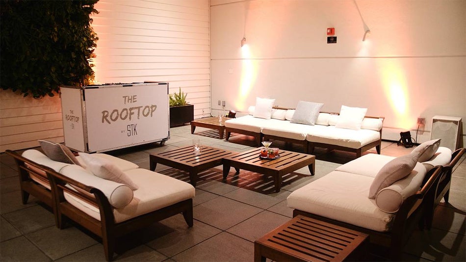 Close up of the lounger are at The Rooftop at STK, wooden couched with white cousins and lamps on the back wall in San Diego, California, USA