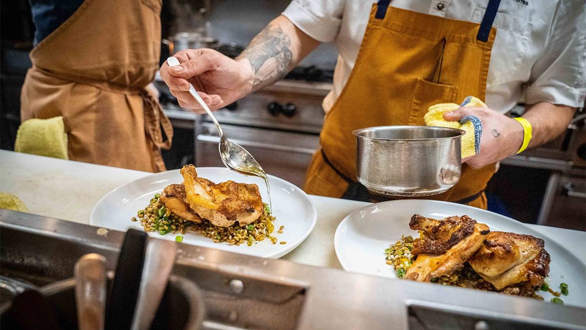 Close up photo of a chef putting the finishing touches on two chicken dishes at Serea Coastal Cuisine in San Diego, California, USA