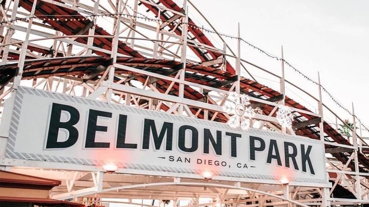 Close up view of the sign for Belmont Park with the Giant Dipper behind it in San Diego, California, USA