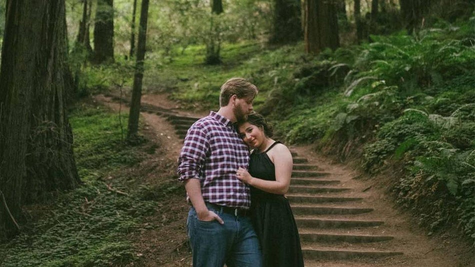 Couple posing for a photo together with wooden stairs leading up into the forrest behind them in Muir Woods in San Francisco, California, USA