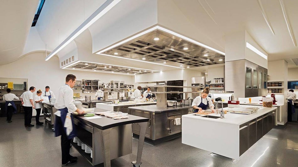 Wide shot of the Kitchen at The French Laundry with stainless steel appliances and countertops and white walls with chefs working in San Francisco, California, USA