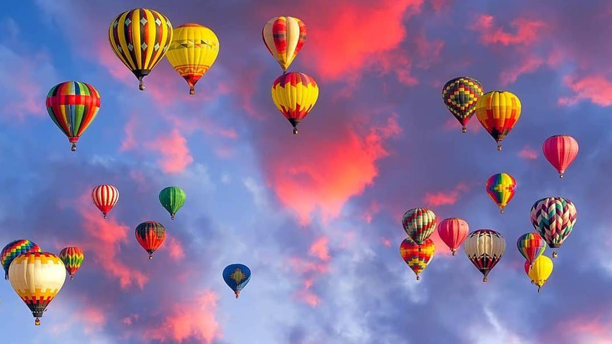 Several hot air balloons in the sky with a pink and purple sunset behind them in San Francisco, California, USA