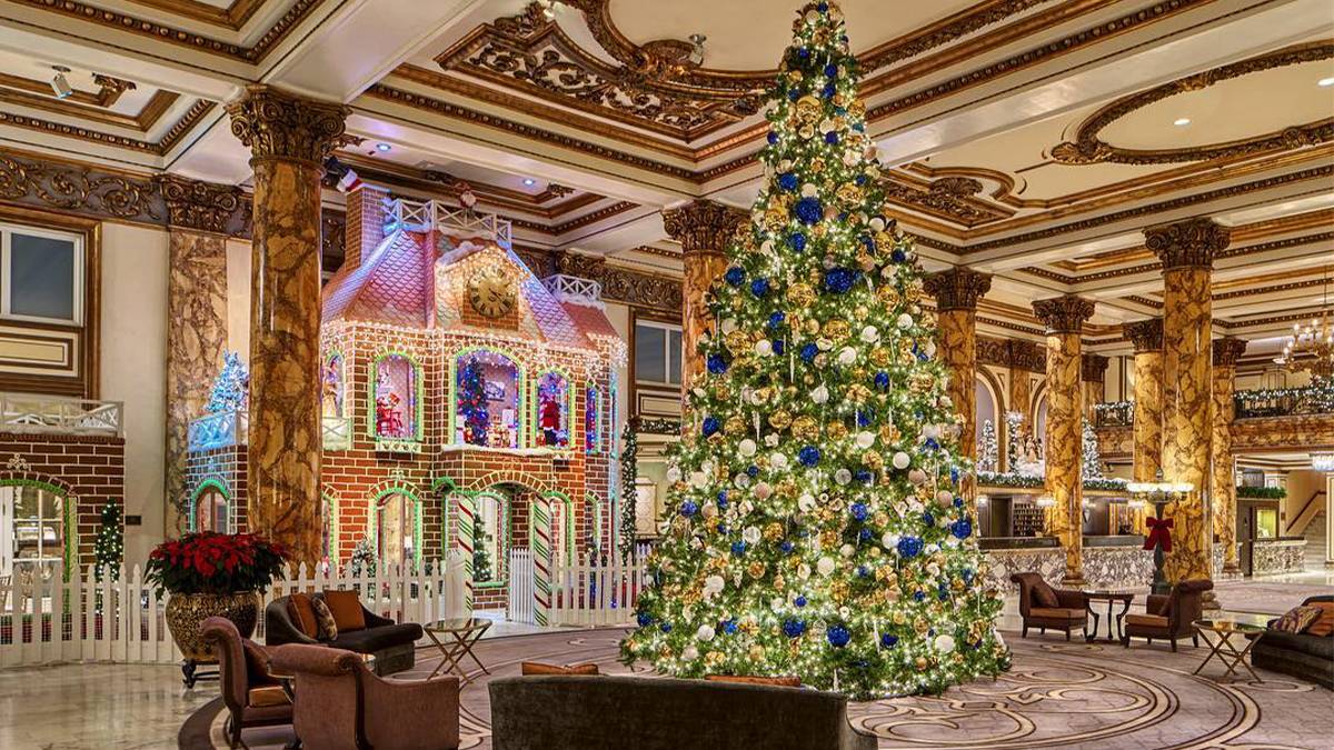Wide shot of the life-size gingerbread house and large Christmas tree at Fairmont Hotel in San Francisco, California, USA