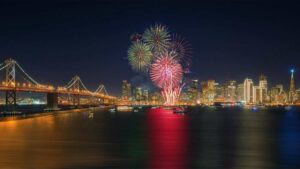 fireworks over bay next to Golden Gate Bridge with cityscape in background in San Francisco, California, USA
