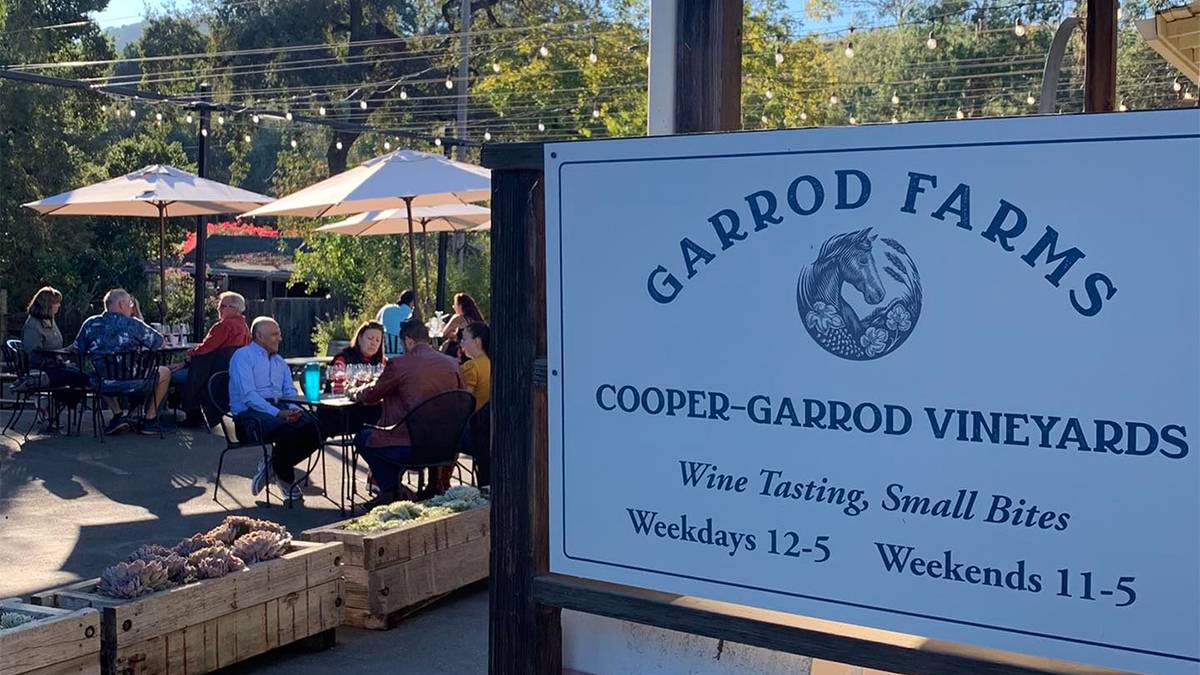 Close up photo of the sign for Garrod Farm Winery with people dining in the back ground on a sunny day in San Francisco, California, USA