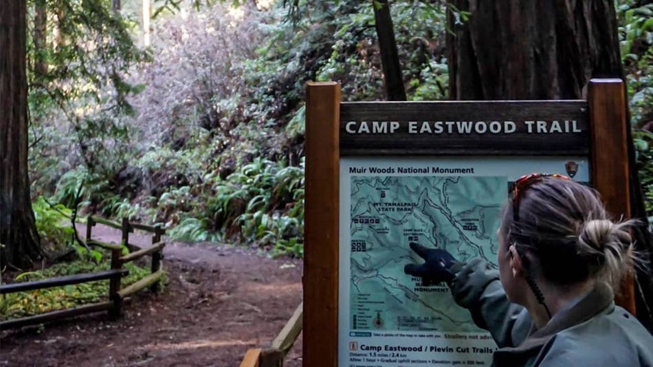 Woman pointing to a map of a trail at Muir Woods in San Francisco, California, USA.