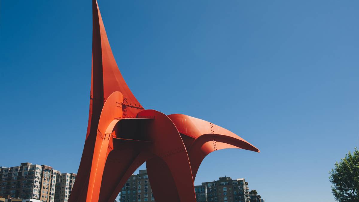 Red eagle sculpture in the Olympic Sculpture Park with the Space Needle in the background in Seattle, Washington, USA