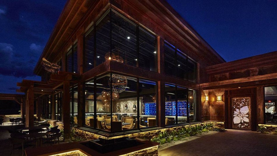 Exterior view of Mariposa Latin Inspired Grill at night with its large glass windows and soft light in Sedona, Arizona, USA
