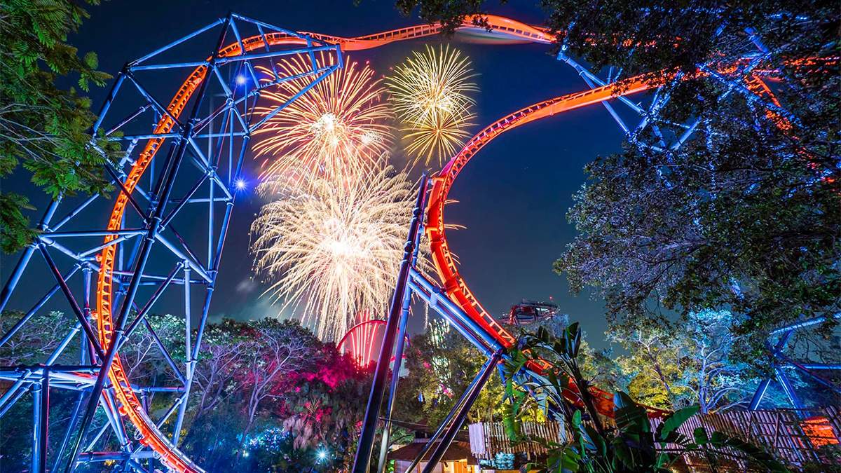 Wide shot looking up at a roller coaster with large bright fireworks behind it at Busch Gardens Tampa in Tampa, Florida, USA