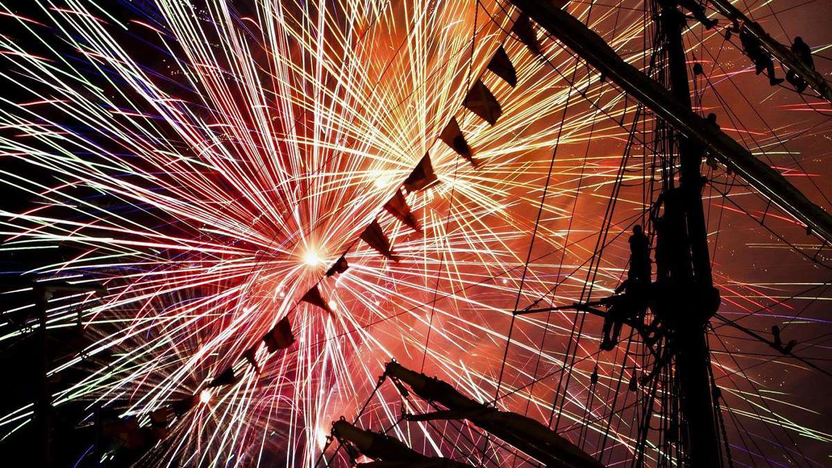 close up of red and orange fireworks behind Recreated Ship staff in Williamsburg, Virginia, USA