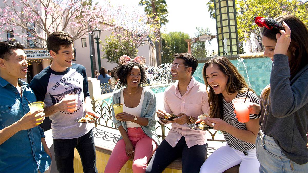 Group of young people, some wearing Mickey ears, drinking different alcoholic beverages at the Disney California Adventure Food & Wine Festival near Los Angeles, California, USA
