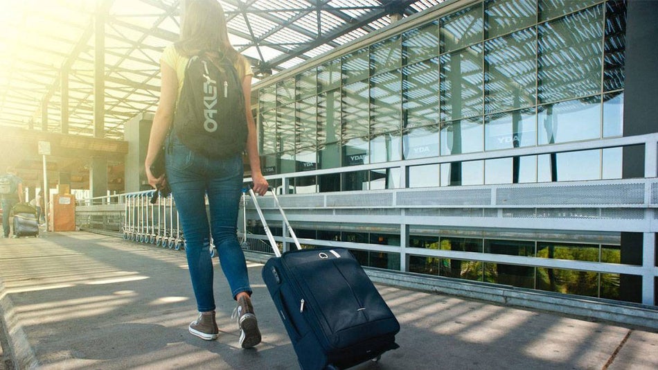 woman traveler walking outside of an airport with luggage