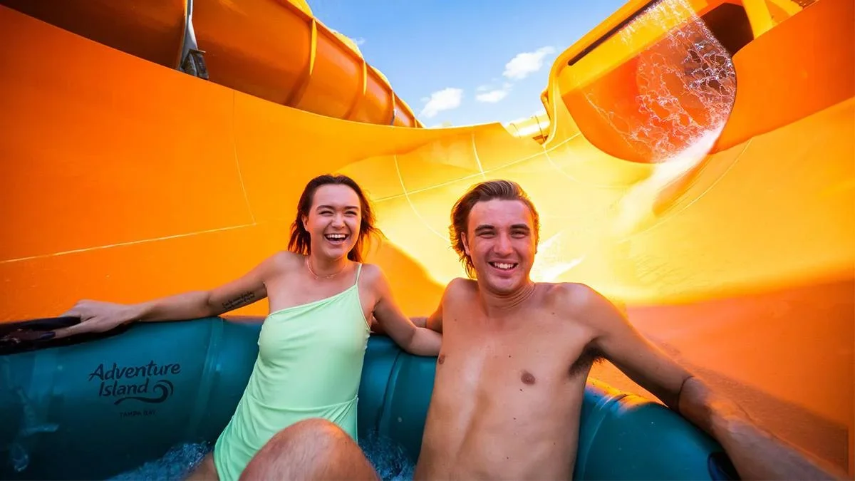 Couple going down a waterslide on a raft on a sunny day at Adventure Island in Tampa, Florida, USA