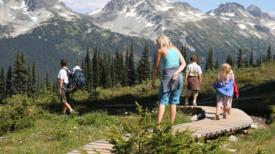 family hiking along a boardwalk surrouned by alpine folliage and mountains in Alaska