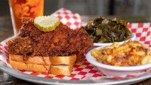 Close up of a meal with spice fried chicken, mac and cheese, and collard greens from Rocky’s Hot Chicken Shack in Asheville, North Carolina, USA