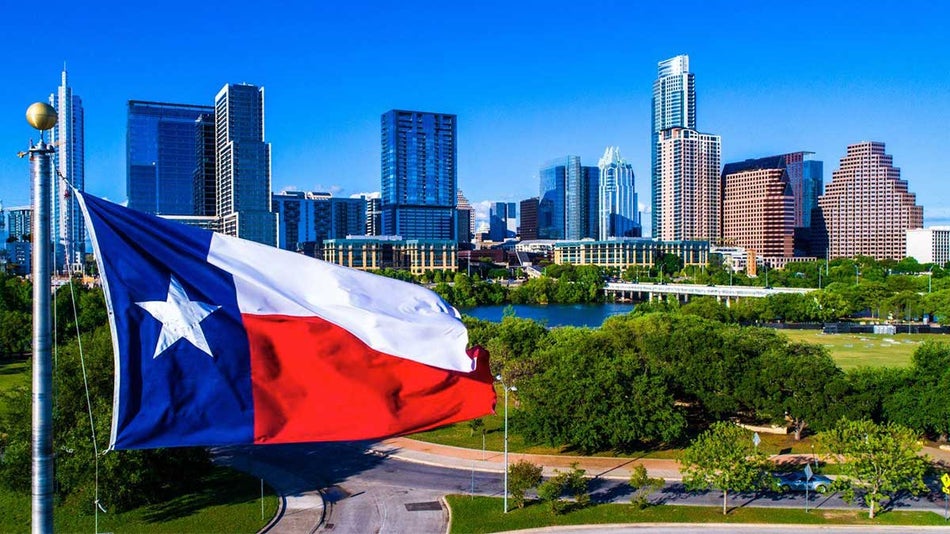 Perfect Texas flag flying in front of Austin, Texas, USA downtown skyline cityscape sunny perfect day